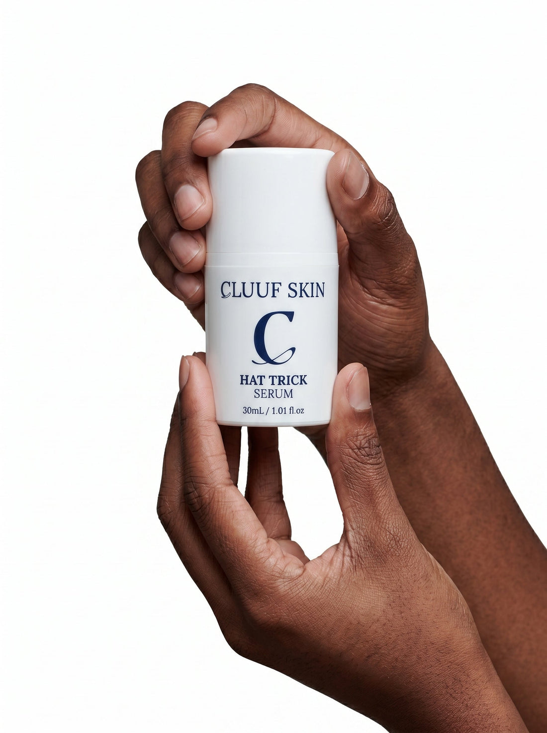 Two dark-skinned hands holding CLUUF Skin Hat Trick Serum bottle, 30mL plant-based serum"